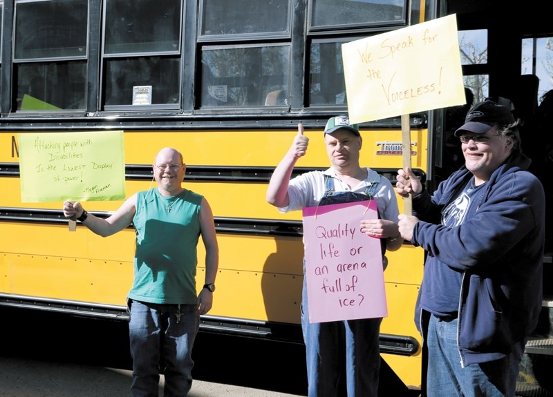 Joe Williams (left), Donnie Greig and Jason Huish hold the signs they took to the Legislature on May 15. The three were among 25 people affected by the pending PDD cuts who