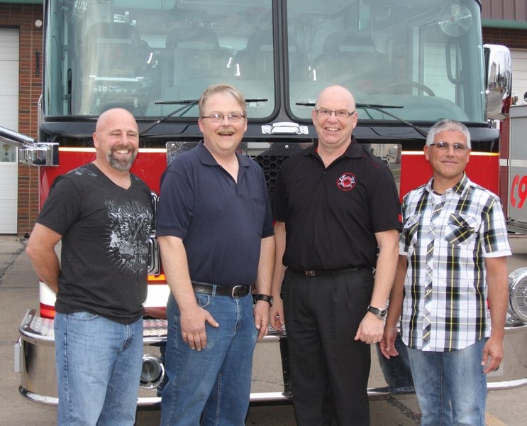 Retiring firefighters Brett Cooper, Don Jewett, Brian Byrnell and Tim Keppy pose for a picture in front of Westlock’s fire truck on Saturday evening at a barbecue held in