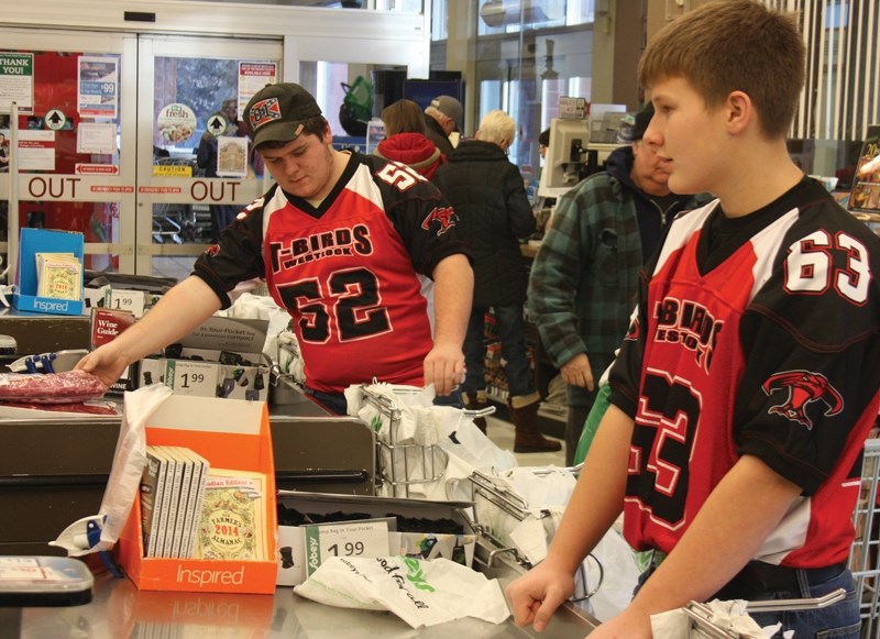 Westlock Thunderbirds Dom Byvank (left) and Braden Anderson took a shift bagging groceries Monday morning to help raise money for the food bank.