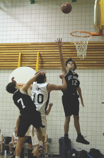 Saint Mary Sharks Justin Biddiscombe (12) and Zach Frith-Smith (7) fight with a J.A. Williams player for a rebound during the two teams’ game in Lac La Biche over the