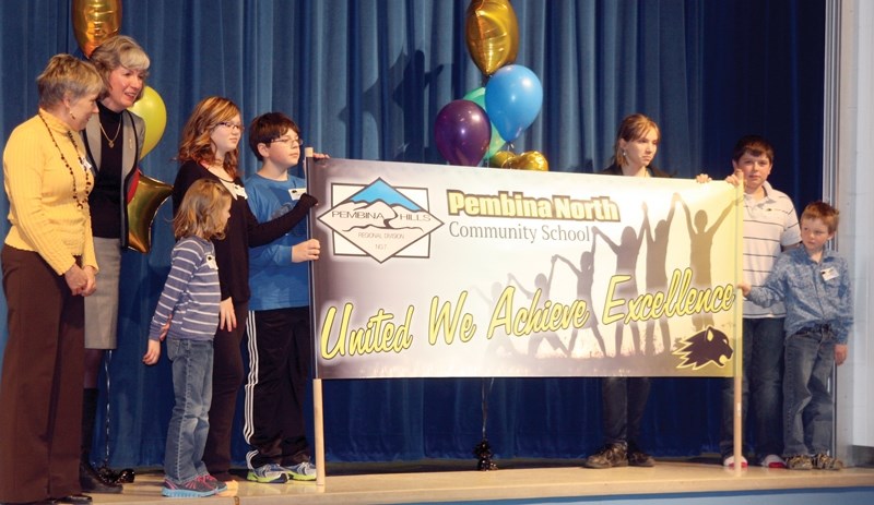 A banner displaying the Pembina North Community School’s purpose statement &#8220;United We Achieve Excellence &#8221; is unfurled on stage at Dapp School following the Jan.