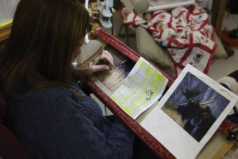 Gail Hove carefully lines up her stitch with the pattern that will turn a photo of a moose into a piece of cross stitching at the Lil Stitchers’ retreat on Saturday.