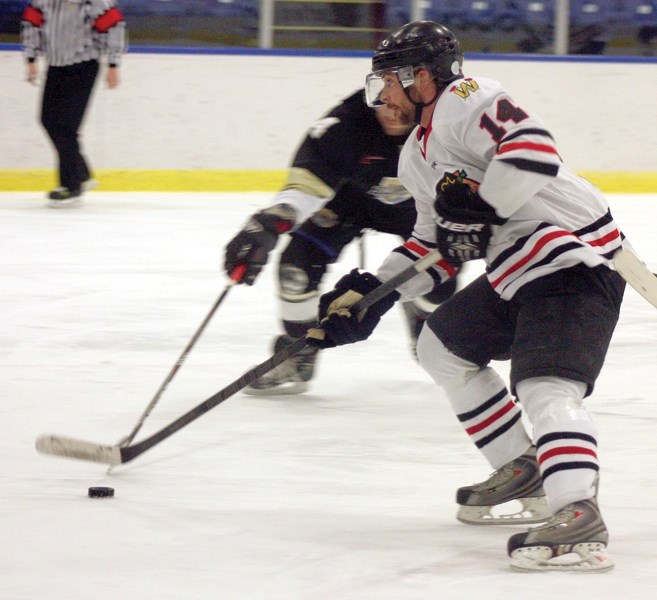 Westlock Warrior Levis Monfette keeps control of the puck against a Devon Baron defender during the teams’ second-round playoff match Feb. 22 in Westlock. The Warriors lost