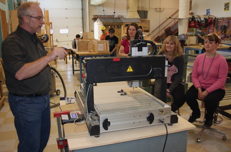 Teacher Kevin MacKenzie demonstrates the use of the school’s CNC (computer numerical control) machine to trustees Jennifer Tuininga, Sheri Watson and Kim Webster during a