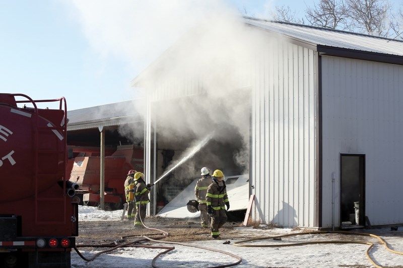 Westlock County firefighters work to douse the remaining flames of a burning tractor inside a shop northwest of Dapp on March 23. Crews were on scene for about two hours and