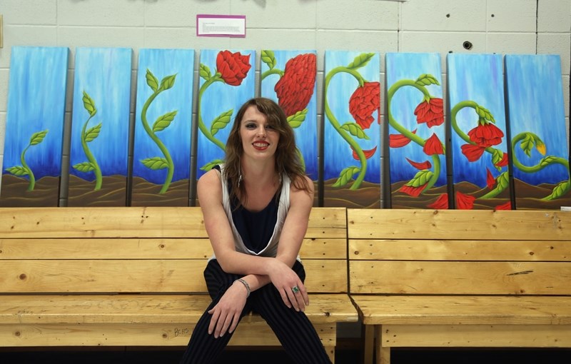 Grade 12 student and artist Valerie McMillan sits in front of one of her pieces on display at the R.F. Staples Senior High Art Show and Sale, The Story of a Flower. McMillan
