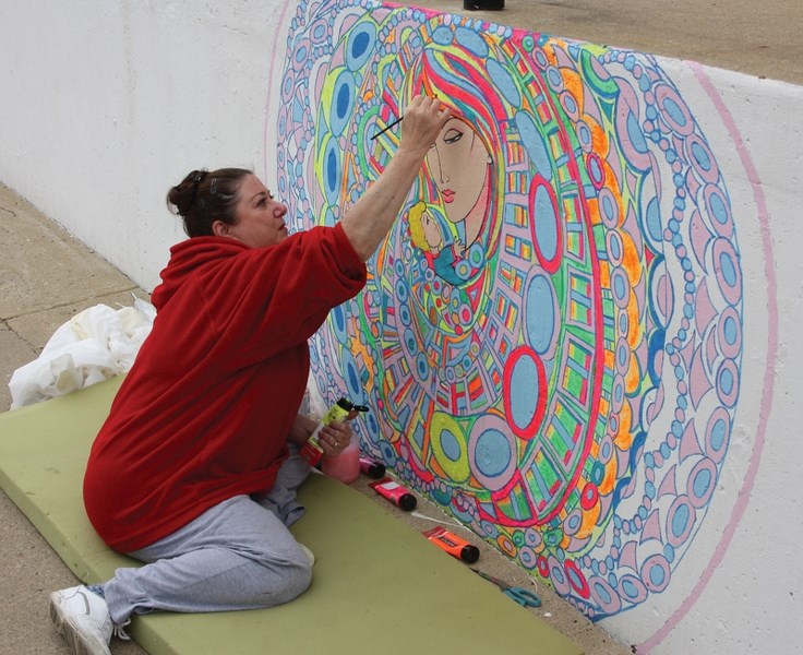 Painter Judith Garcia works on the mural of the Virgin Mary and Baby Jesus she painted at the front step of St. Mary’s Catholic Church. She has been working on the mural