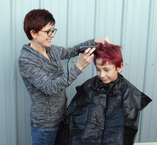 Curtis Plamondon (right) raised $1,360 for the The Kids With Cancer Society by shaving his head. Working the clippers at the Nov. 3 event is Lisa Boulerice.