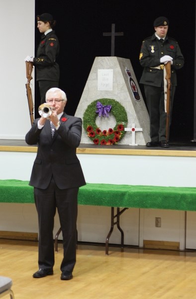 Trumpeter Alex Schabert plays taps while in the background, Westlock cadets Mackenzie Lunger (left) and Joe Fallows guard the cenotaph at the Westlock Nov. 11 event.