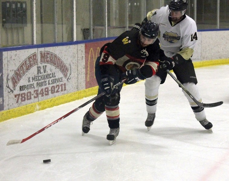Warrior Gord Bell fights for a loose puck with a Devon Baron during the club’s 3-1 Friday-night home victory in Game 1 of the NCHL championship.