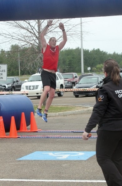 Matt McQuilken-Vida jumps for joy, touching the top of the finish line arch at Saturday&#8217;s Spirit of Westlock Triathlon.