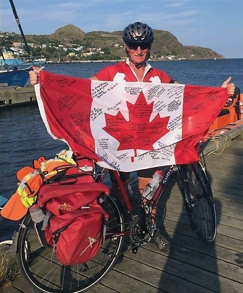 Westlock’s Bryan Carnegie holds up the Maple Leaf after arriving in St. John’s, NL Aug. 22. Carnegie completed the 7,000-plus kilometre coast-to-coast ride in 65 days.