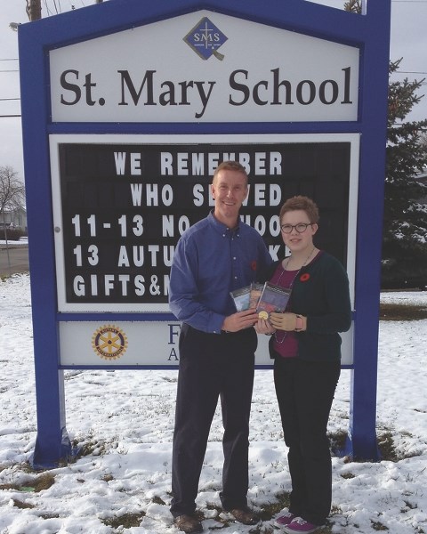 Westlock CHAMP Sawyer Dutka (right) presents St. Mary School associate principal Vance Nakonechny with documentaries from the War Amps Military Heritage Series as part of