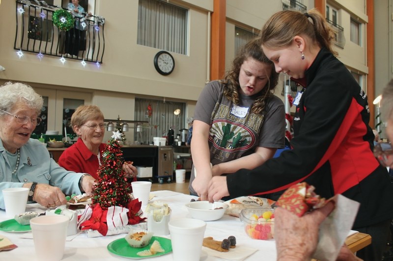 L-R: Rose Padleinski and Doreen Baker watch as Haley Halle and Katy Wiks from the R.F. Staples Women’s Leadership Group prepare freshly decorated gingerbread men Dec. 5.