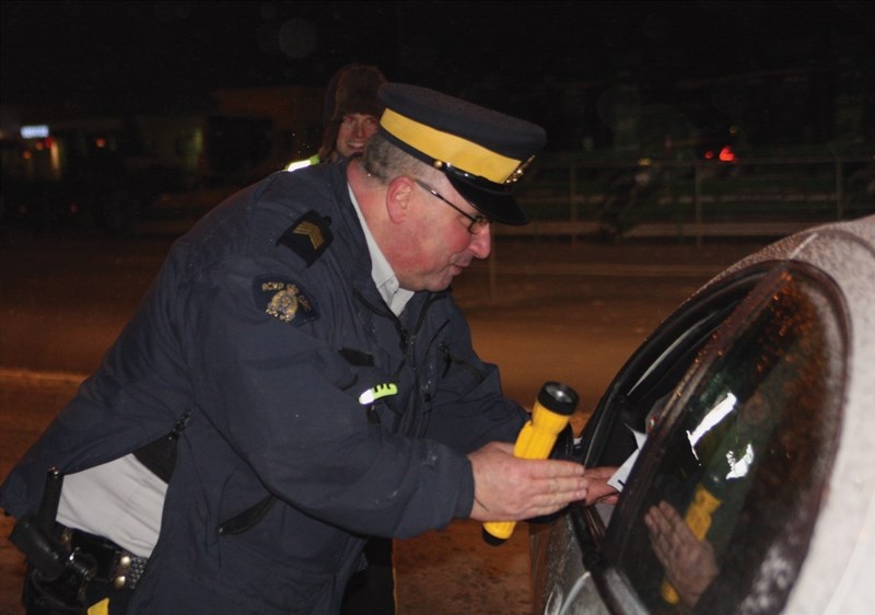 Westlock RCMP Staff Sgt. Dwayne Rawson speaks with a driver on Friday, Dec. 11 during the Candy Cane Checkstop campaign.