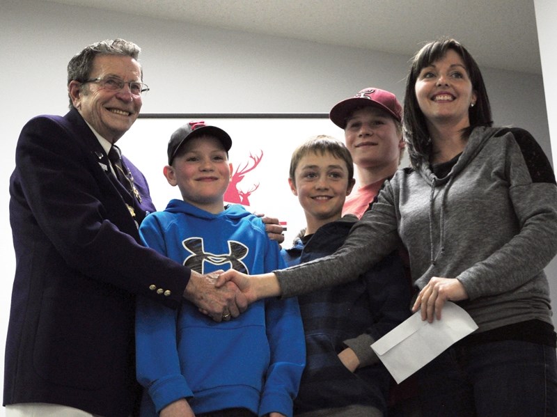 L-R: Eleanor Hall Students Brady Harbin, Kaden McCoy and Cooper Harbin stand between former Elks president Harry Marshall shaking hands with Linda McCoy president of the
