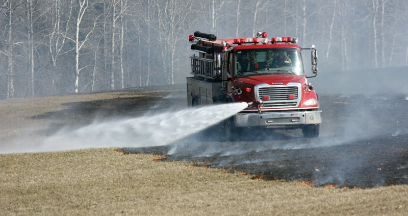 Westlock Rural firefighters soak the grass at a brush fire east of Vimy April 7. County fire chief John Biro says the wind caught sparks from a backyard campfire and burned