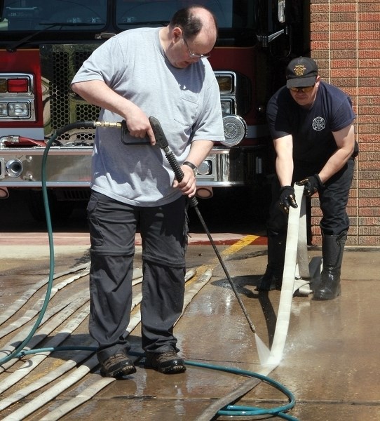 Westlock Fire Department’s Bill Smith (left) and Rick Duiker hose down equipment after returning from Fort McMurray on Friday, May 13. In total 16 area firefighters helped