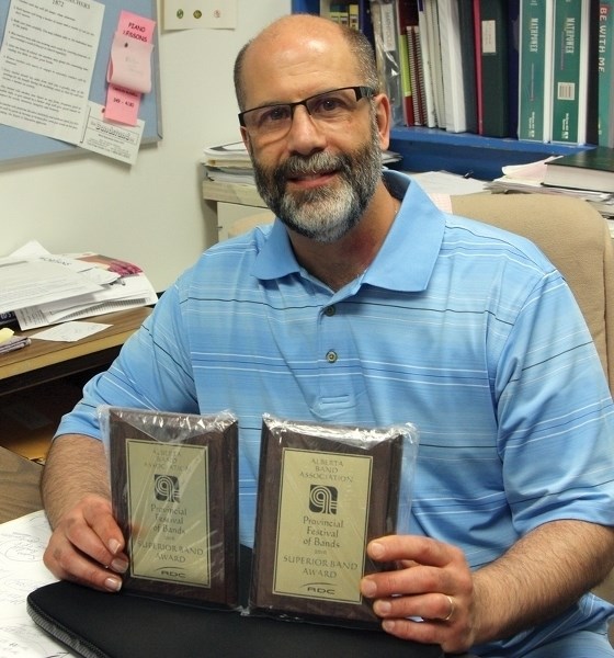 St. Mary School band teacher Oscar-Jose Garcia poses with his band’s superior performance awards. Garcia’s swan song with the band will take place on June 2 at CATS Theatre.