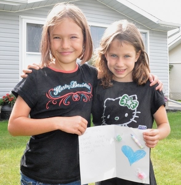 Calli Hehn (left) and Sara-Lauren Bowsfield hold get-well card similar to the ones the pair distributed to other victims of last week’s flood.