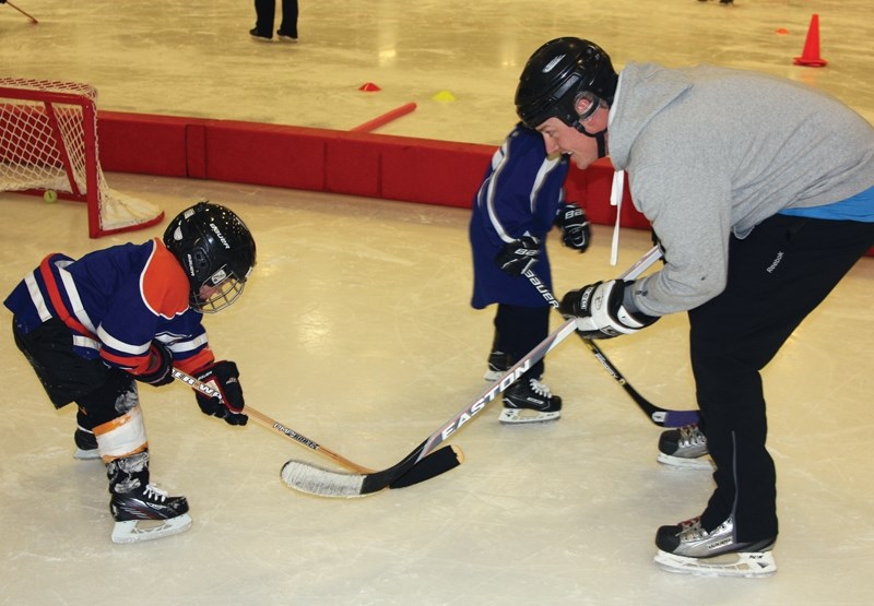 Andrew Carson (right) coaches Denver Nolan as he carefully skates across the ice at I Love Hockey on Saturday.