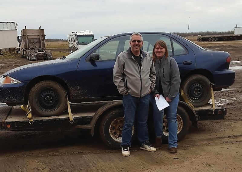 Clyde’s Stu Lorencz has been giving cars to people impacted by the Fort McMurray wildfire. Jessica Yeoman and her husband Brian Doucette stand next to their new car.