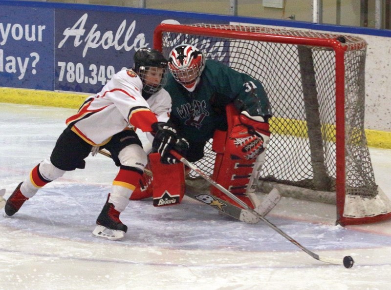 Midget Warriors’ Addison Weir chases a rebound off Wembley Wildcats goaltender Ian Brix during their first game of the 12th annual Gord Smith Memorial tournament Dec. 3 at