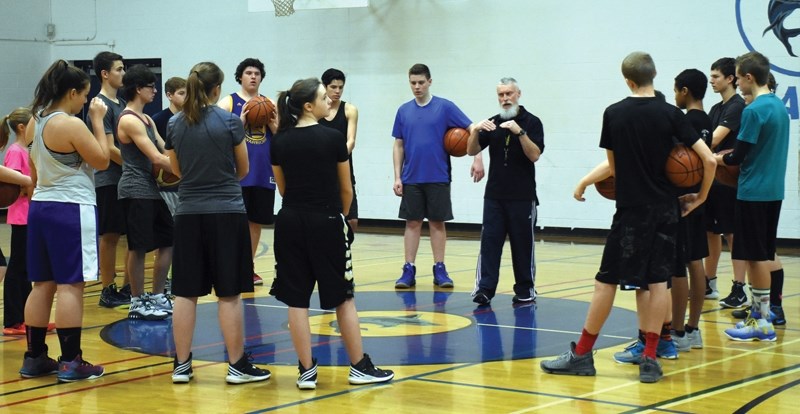 Coach Chris Nicol (ecntre) goes through basketball basics with 18 students from St. Mary School and R.F. Staples. Nicol, who has 35 years of coaching experience, ran a