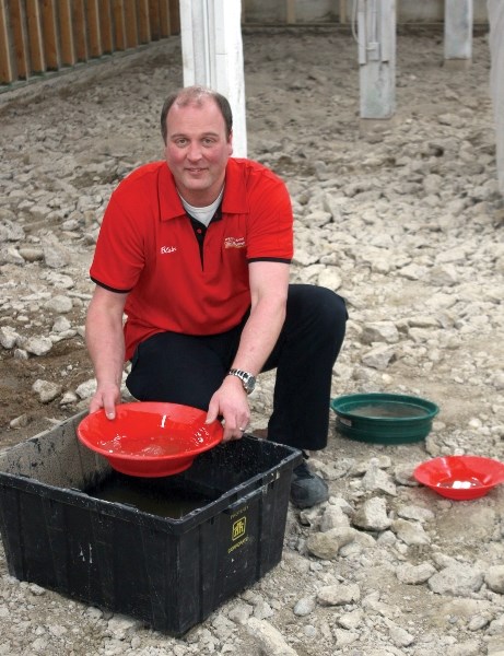 Blair Kneller sifts through some crushed gravel in the basement of his Home Hardware store. Kneller recently discovered that he could pan for gold in the remains of his