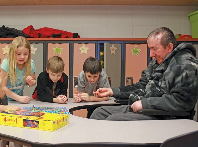 (l-r) Kylee Lemke, Jax Swingen and Logan Gibert play a game of snakes and ladders with Richard Schmaltz during