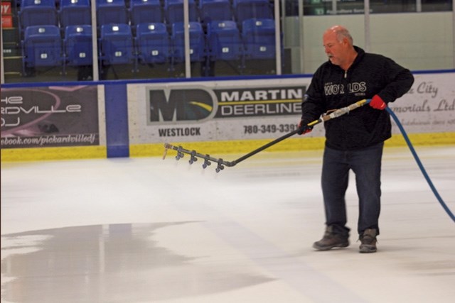 Jamie Bourassa sprays white paint on the ice at the Rotary Spirit Centre as crews prepare to lay out the special ice for the Boston Pizza Cup Feb. 3.