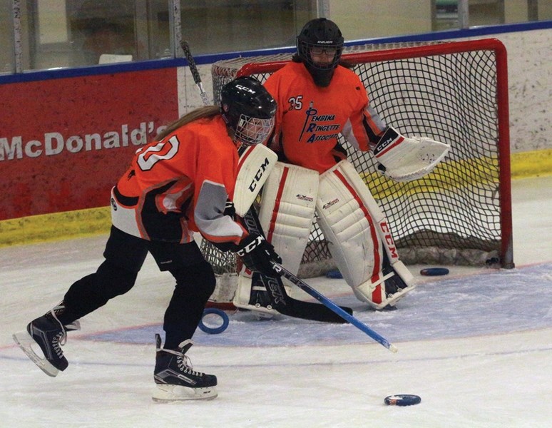 Pembina U14B-1 Rock player Jade Issac reaches out for the ring as goaltender Paige Brill prepares to make a save during a practice at the Rotary Spirit Centre March 10.