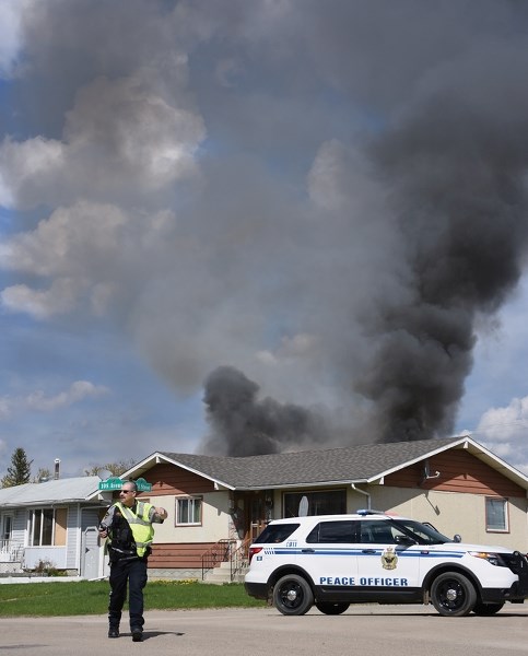 Town of Westlock community peace officer Randy Burgess directs traffic on the corner of 108 Ave. and 103A St. while a tower of black smoke bil-lowed out of a burning garage