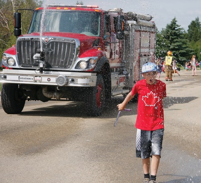 Austin Baltzel gets sprayed by the Pickardville fire department during the July 1 parade in the hamlet.