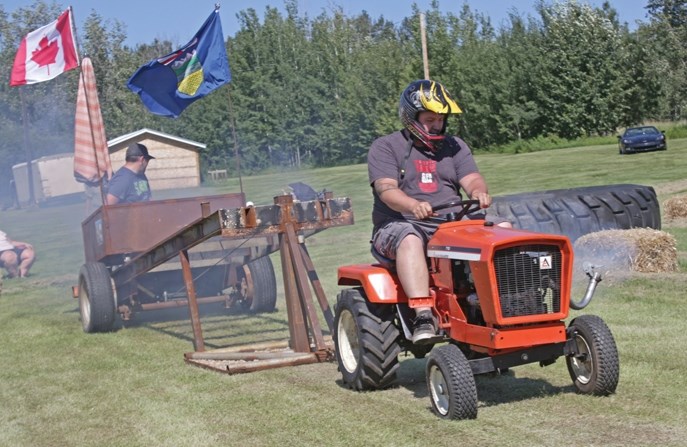 Dustin Gibson smokes the competition during the weight-pull portion of the lawnmower race. ABOVE: Classic cars lead off the parade through the hamlet.