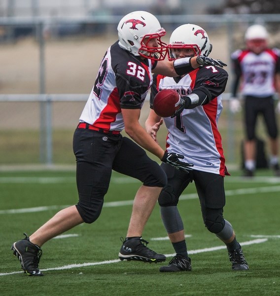 Thunderbird quarterback Aiden Walker (7) hands the ball off to Robert Bokenfohr (32) during the opening quarter of an exhibition game against the Bellerose Bulldogs at Riel