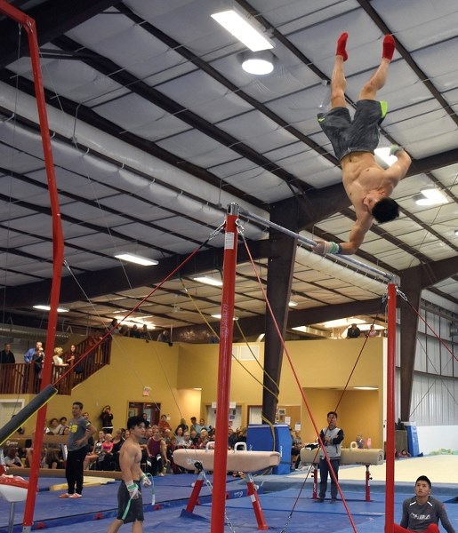 Chinese National Games and Worlds gold medallist and Olympic bronze medallist Lin Chaopan twists on the high bar at the Pine Valley Gym Cen-tre Sept. 23. The gymnasts are