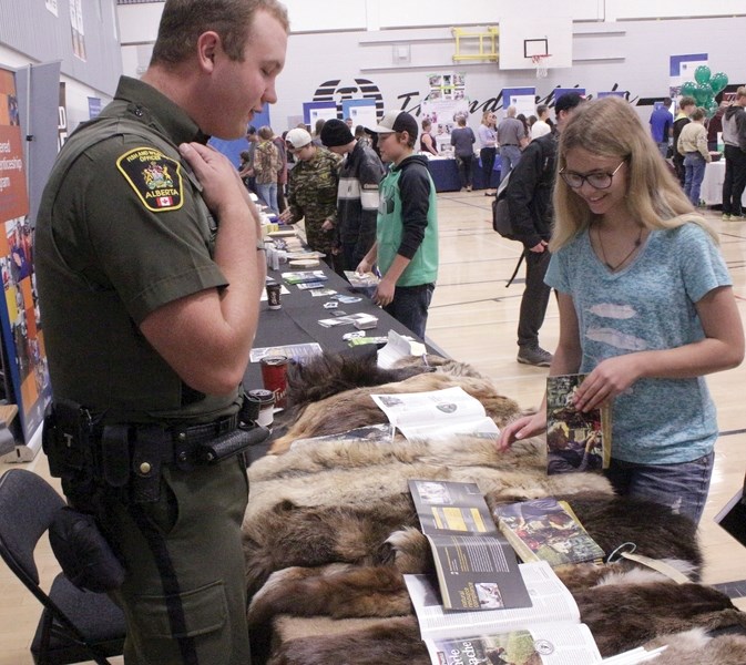 Alberta Fish and Wildlife officer Levi Neufeld shows off some animal pelts to Savannah Turner at the Making Connections &#8211; Face to Face Career Fair and School Expo at