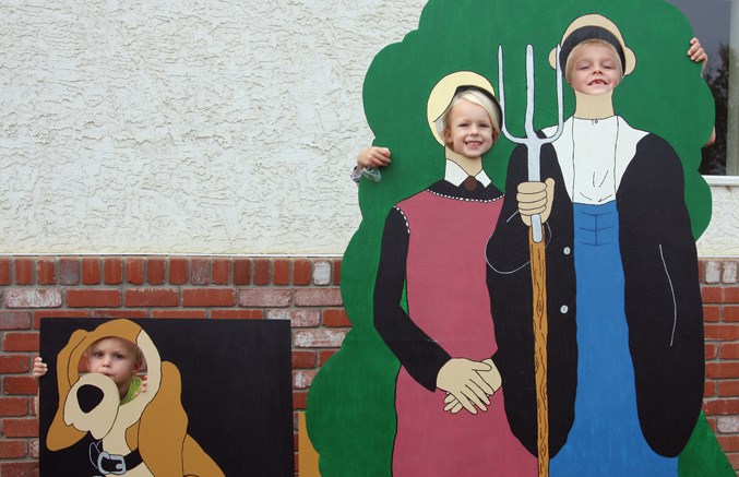  ake, Ella, and Connor King pose in some of the wooden cut-outs available for the children at Westlock County’s 75th anniversary celebrations at the Canadian Tractor Museum Aug. 25.