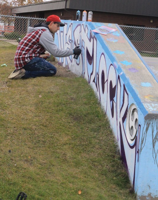  Edmonton-based graffiti artist Jordan Ernst painted the new mural at the skate park which was finished Sept. 28. Pictured, Ernst spray paints the town tag while kids did their own graffiti that day.