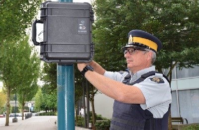 A Mountie installing a Black Cat radar device on a pole.