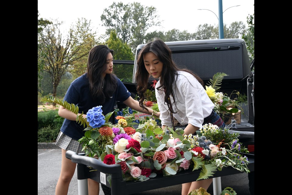 Yolanda Yang and Isabella Zhang unload donated flowers at R.J. Kent Residences in Port Coquitlam.