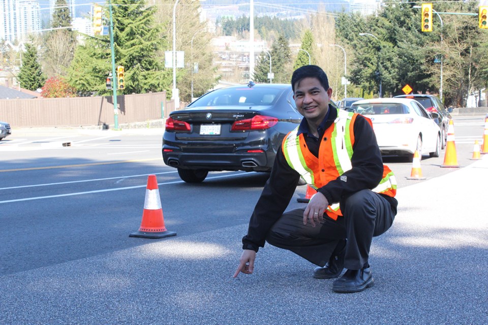 Edwin Dela Rosa, Coquitlam’s manager for the High Friction Surface Treatment (HFST) project, is pictured on Mariner Way near the Dewdney Trunk Road intersection. He is pointing out the difference between the pavement and the HFST layer.