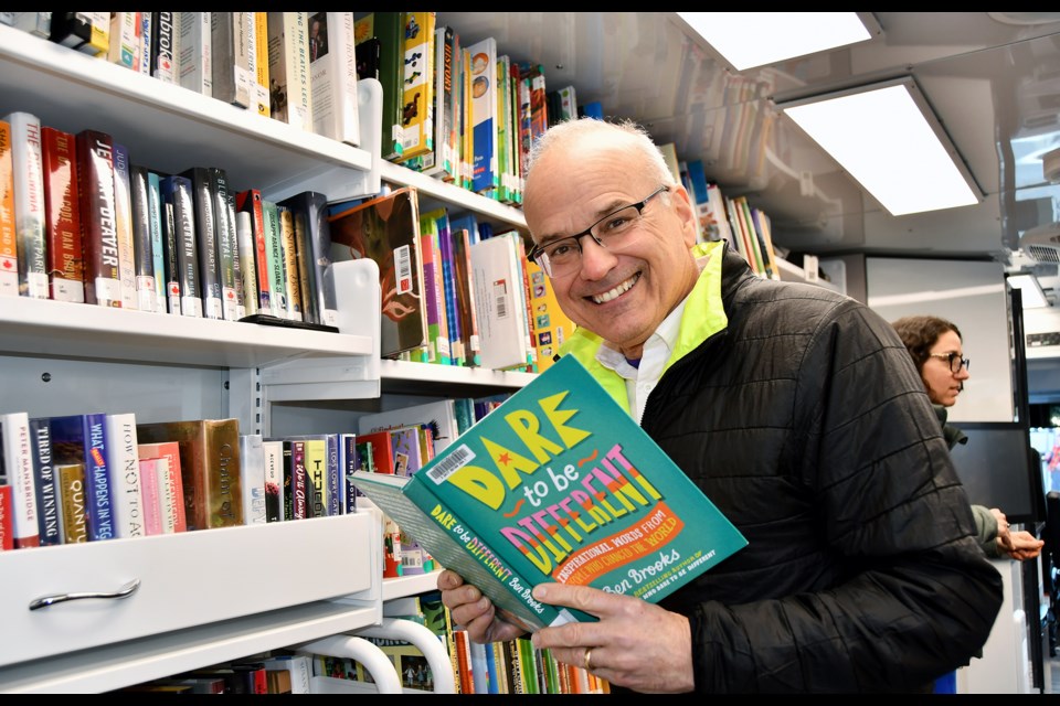 Coquitlam Mayor Richard Stewart picks up a book on the new Library Link on Feb. 6, 2024.