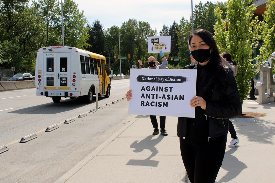 Gina Chong of Port Moody holds a sign outside of the Inlet Centre SkyTrain station on the inaugural Day of Action.