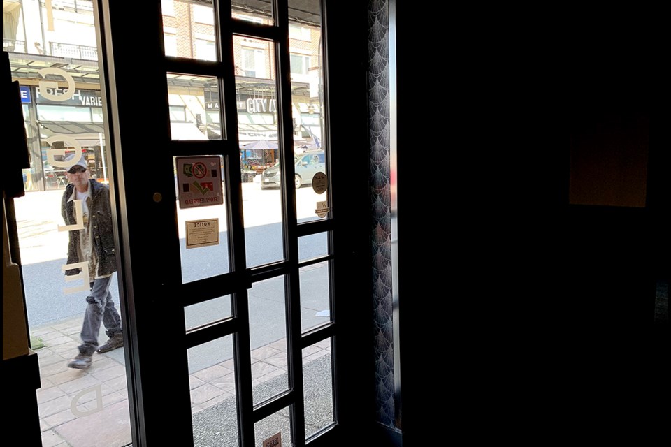 A passerby on Shaughnessy Street tries to catch a glimpse inside the old Giggle Dam theatre as its fixtures and contents are prepared to be auctioned off following its closure.