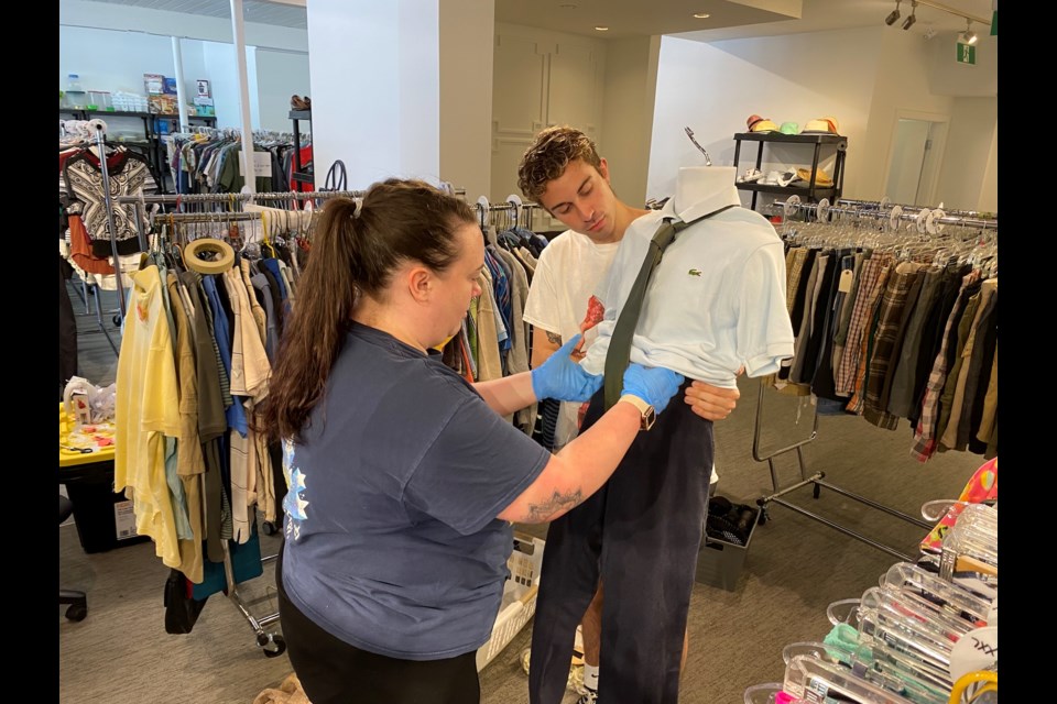 Nathan Piasecki, a staff member, and Bryanna Saggers, store manager, dress a mannequin for the new Thrift and Fund store that opens Saturday, June 3 at Burquitlam Plaza.