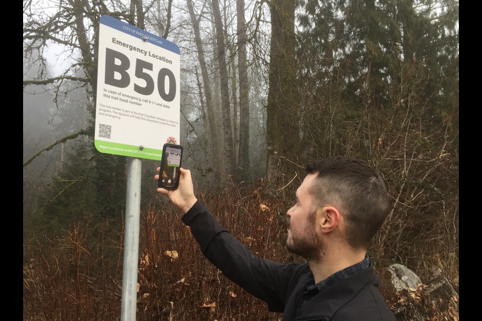 Port Coquitlam is installing trail markers to make it easier for police and fire fighters to respond to emergencies. Mayor Brad West demonstrates the QR code.