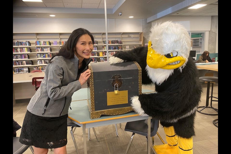 Gleneagle Secondary principal Wendy Yu with Talon, the Gleneagle mascot. They are closely examining a 25-year-old time capsule, which will soon be opened.