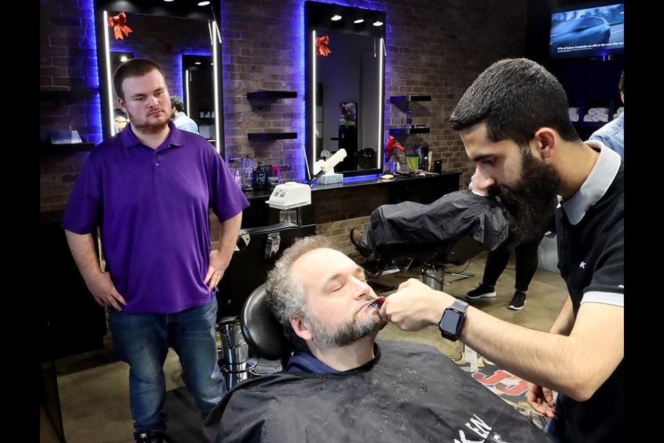 Austin Chassie, a grade 12 student at Port Moody Secondary School, supervises the wacky moustache being created for one of his teacher, Neil Canuel.